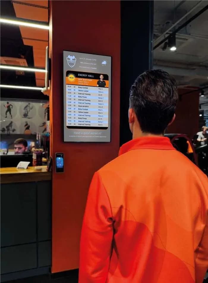 Staff member looking at a vertical schedule screen at the club entrance