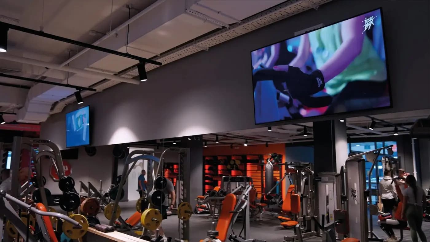 Gym floor with large screens above the equipment
