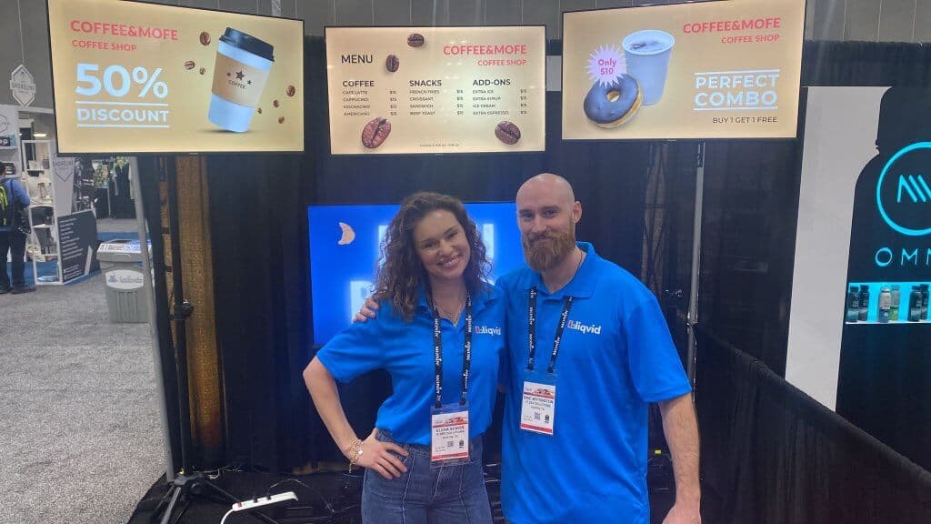 Two Liqvid team members in front of three coffee shop menu screens with a discount, a menu and a combo offer